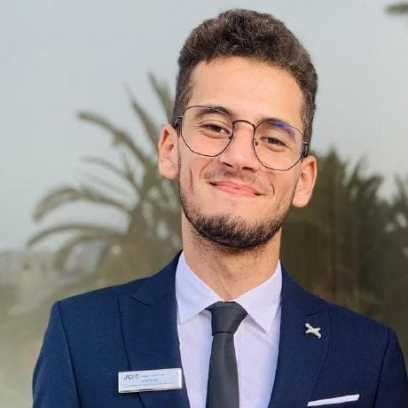 Mohamed Jalel Dridi, smiling, in a navy suit and glasses